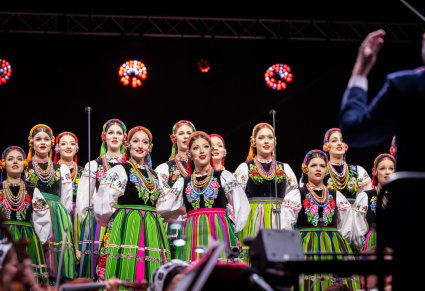 Zbliżenie na solistki i część chóru w kostiumach łowickich