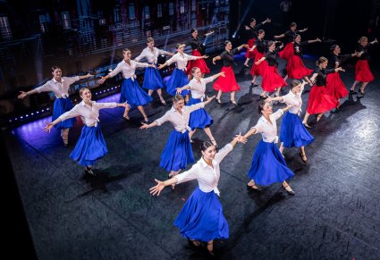 Na scenie grupa Artystek we współczesnych kostiumach podczas wykonywania choreografii tanecznej na scenie