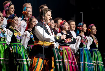 Solista w kostiumie łowickim w tle reszta chóru również w kostiumach łowickich