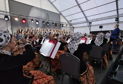 Widok z boku na orkiestrę w kostiumach wilanowskich, Dyrektora zespołu i chór w kostiumach łowickich