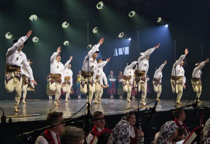 Na cenie Artyści w kostiumach podhalańskich w trakcie wykonywania choreografii tanecznej , niżej widoczna część Orkiestry