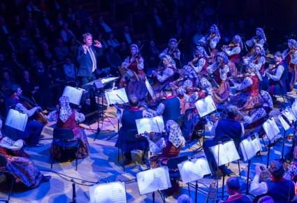 Dyrygent zwrócony w stronę Orkiestry, widać również pierwsze rzędy publiczności