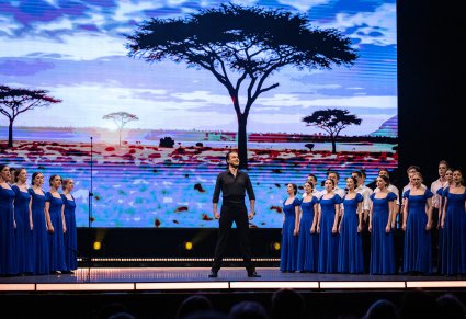 Na środku sceny Solista po bokach Artyści Chóru w kostiumach współczesnych śpiewający utwór Medley