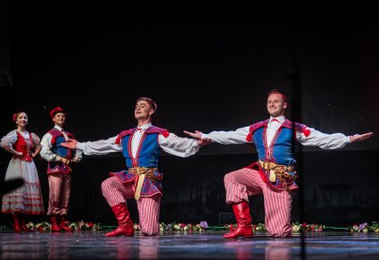 Artyści w czasie wykonywania choreografii tanecznej w kostiumach stylizowanych na kostium krakowski