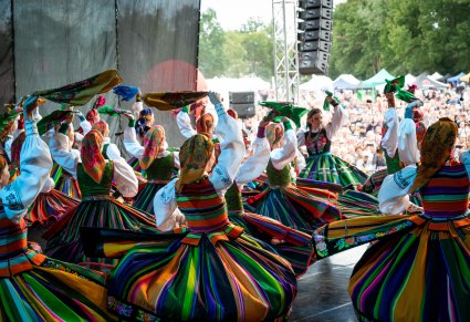 Zdjęcie Artystek w kostiumach łowickich kręcących się na scenie i machających chustami