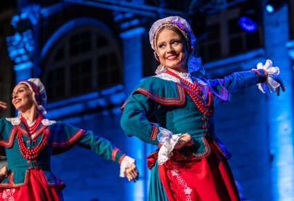 Dwie Artystki w kostiumach kujawskich na scenie wykonujące choreografię taneczną