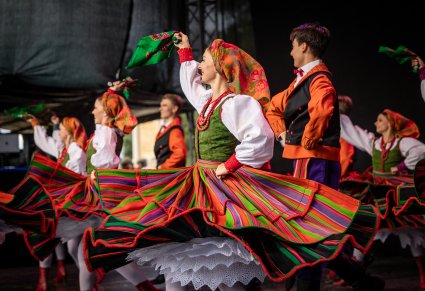 Artyści w kostiumach sannickich na scenie podczas wykonywania choreografii tanecznej
