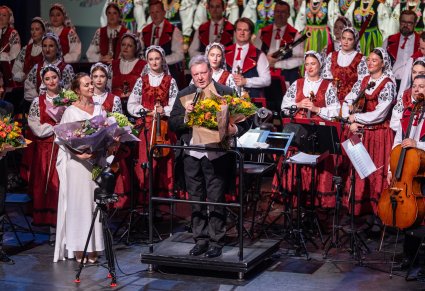 Na pierwszym planie Dyrektor Jacek Boniecki trzymający kwiaty, obok niego Solistka z kwiatami a za nimi Orkiestra
