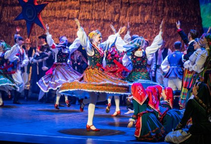 Na pierwszym planie na scenie kręcące się Artystki w kostiumach ludowych