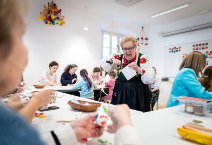 Na pierwszym planie prowadząca warsztaty w trakcie tłumaczenia uczestnikom technik wycinania