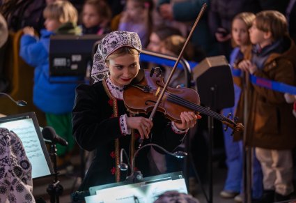Zbliżenie na Muzyczkę w kostiumie wilanowskim, grającą na instrumencie smyczkowym