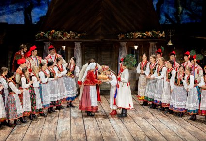 Na środku sceny Panna Młoda całująca chleb, którzy trzyma postać Kliminy, po bokach sceny Artyści w kostiumach krakowskich