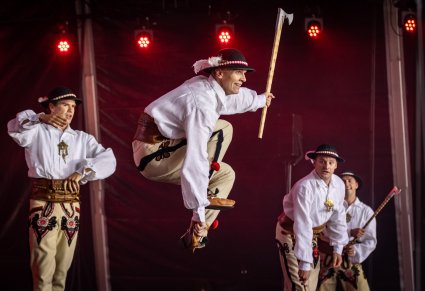 Czterech Artystów w kostiumach podhalańskich. Jeden z nich wykonuje spektakularne figury taneczne