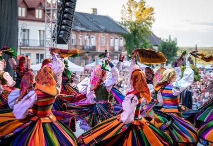 Widok na kręcące się Artystki w kółko i machające chustami na scenie. Artystki ssą w kostiumach łowickich
