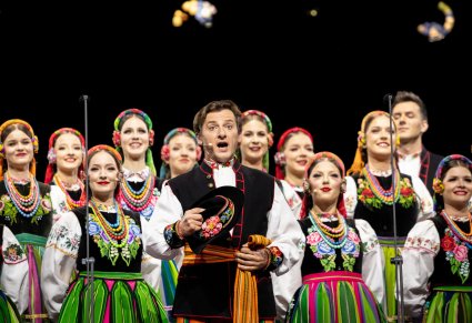 Artyści chóru, na czele z solistą, wszyscy w kostiumach łowickich, podczas wykonywania "Furmana"