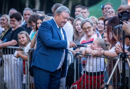 Uśmiechnięty Dyrektor Jacek Boniecki trzyma mikrofon dziewczynce z publiczności