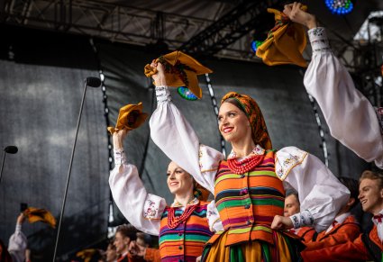 Artystki w kostiumach łowickich machające chustami w stronę publiczności