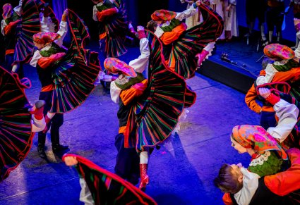 Pary Artystów zespołu "Mazowsze" w kostiumach sannickich podczas wykonywania choreografii tanecznej na scenie
