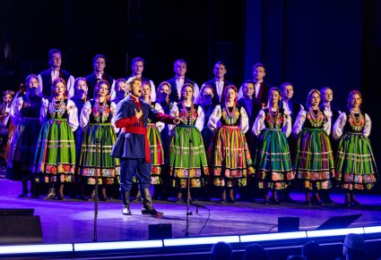 Na scenie solista w kostiumie kujawskim a za nim grupa Artystów Chóru w kostiumach łowickich