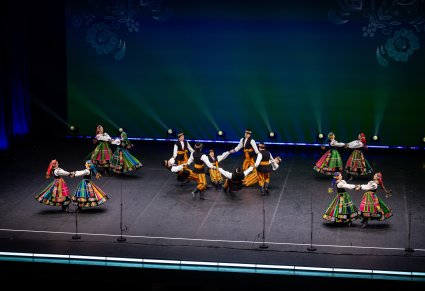 Na scenie Artyści w kostiumach łowickich w trakcie wykonywania choreografii tanecznej