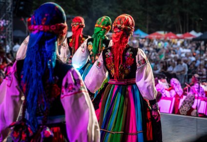 Artystki stojące tyłem do zdjęcia w kostiumach łowickich