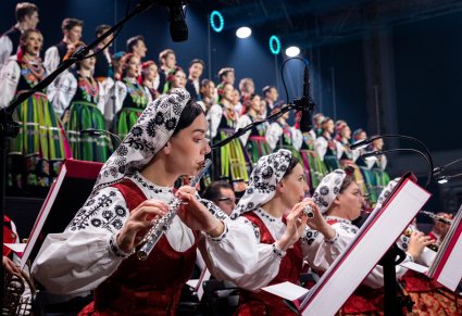 Na pierwszym planie Artystki Orkiestry w kostiumach wilanowskich, na scenie Artyści Chóru w kostiumach łowickich