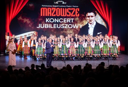 Dyrektor przemawiający na scenie, w tle widoczny chór i koncferansjer