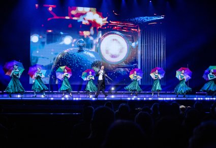 Na scenie Artystki i Solista w kostiumach współczesnych trzymający w ręku parasole, wykonujący choreografię taneczną do utworu Medley