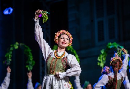 Zbliżenie na Artystkę w kostiumie lubuskim trzymająca kiść winogrona