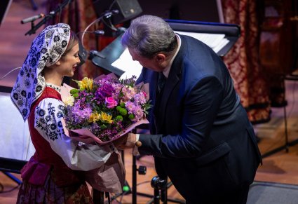 Członkini Orkiestry w kostiumie wilanowskim wręczająca kwiaty Dyrektorowi zespołu "Mazowsze"