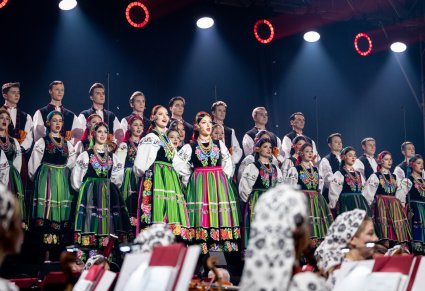 Na pierwszym planie para Solistek, za nimi Artyści Chóru w kostiumach łowickich