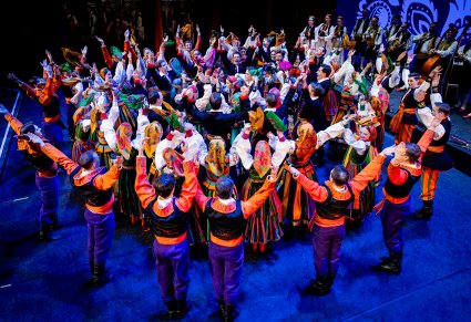 Artyści zespołu "Mazowsze" w kostiumach ludowych podczas wykonywania choreografii tanecznej na scenie