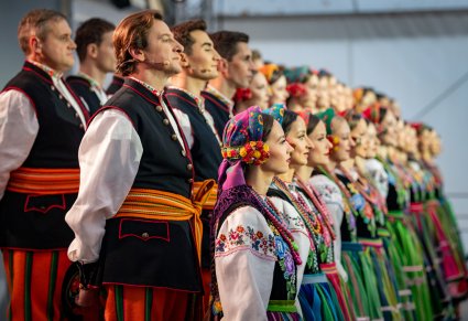 Widok z boku sceny na chór w kostiumach łowickich, podczas koncertu