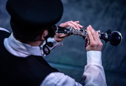 Zbliżenie na Artystę w kostiumie Żyda grający na klarnecie