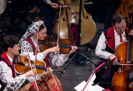 Zbliżenie na trzech Artystów Orkiestry w kostiumach wilanowskich w trakcie gry na instrumentach smyczkowych