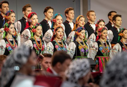 Częśc chóru w kostiumach łowickich, poniżej widoczną część orkiestry w kostiumach wilanowskich