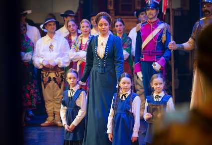 Na pierwszym planie postać Mieszczki wraz z dwójką Dzieci z Wrześni w tle reszta postaci z widowiska