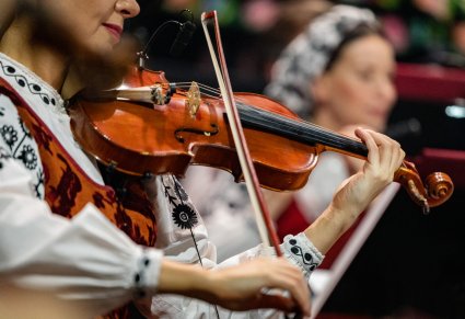 Zbliżenie na instrument smyczkowy, trzymany przez Artystkę Orkiestry w kostiumie wilanowskim