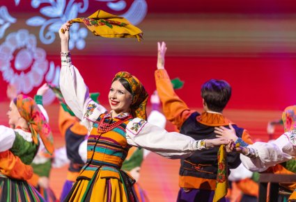 Zbliżenie na Artystkę w kostiumie łowickim podczas wykonywania choreografii tanecznej