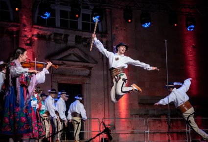 Dwóch Artystów na środku sceny wykonujacych akrobacje taneczne z wykorzystaniem góralskich ciupag