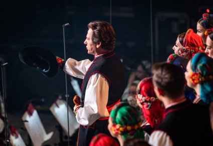 Na pierwszym planie solista a w tle Artyści w kostiumach łowickich