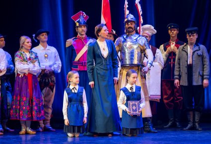 Na pierwszym planie postać Mieszczki wraz z dwórką Dzieci z Wrześni w tle część postaci z widowiska