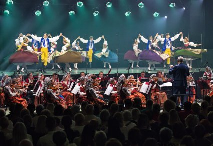 Na scenie Artyści Baletu w kostiumach rozbarskich w trakcie wykonywania choreografii tanecznej, niżej Orkiestra w kostiumach wilanowskich wraz z Dyrygentem