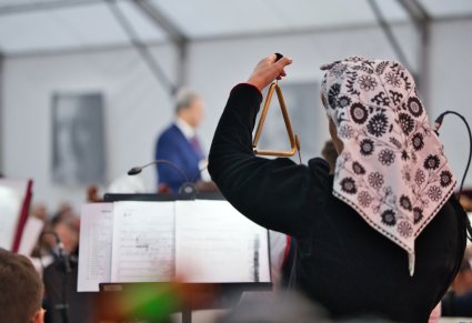 Zbliżenie na muzyka grającego na trójkącie, widoczne elementy kostiumu wilanowskiego