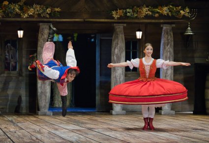 Tancerka wraz z Tancerzem w kostiumach stylizowanych na ludowe w trakcie wykonywania imponującej choreografii tanecznej