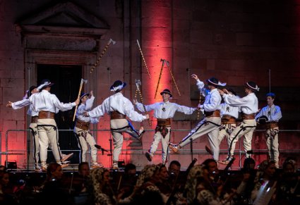 Grupa Artystów w kostiumach podhalańskich wykonujących choreografię taneczną na scenie