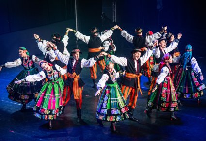 Artyści w kostiumach łowickich podczas wykonywania choreografii tanecznej na scenie
