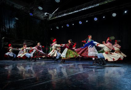 Pary Artystów w kostiumach krakowskich na scenie wykonujące choreografię taneczną