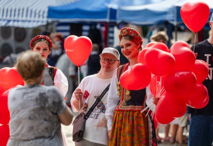 Artystki w kostiumach krakowskich rozdające czerwone balony uczestnikom Pikniku