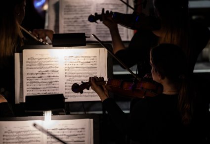 Zbliżenie na Muzyczki grające na instrumenty smyczkowe zwrócone w stronę nut